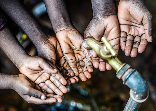 Three African children holding their hands under a tap. Symbol for the importance of water in African countries.